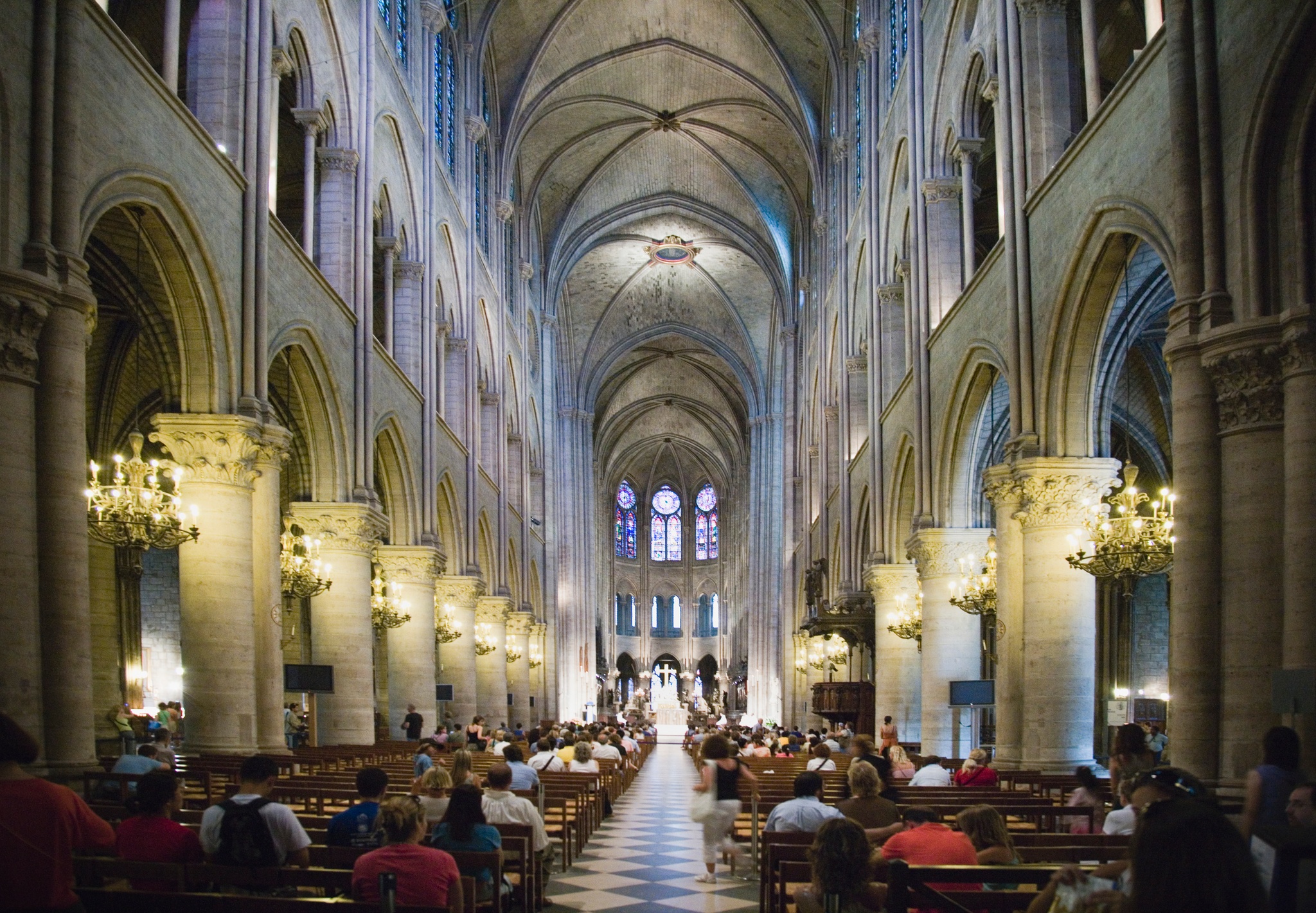 A view down the aisle of a cathedral nave with people seated in chairs on either side 