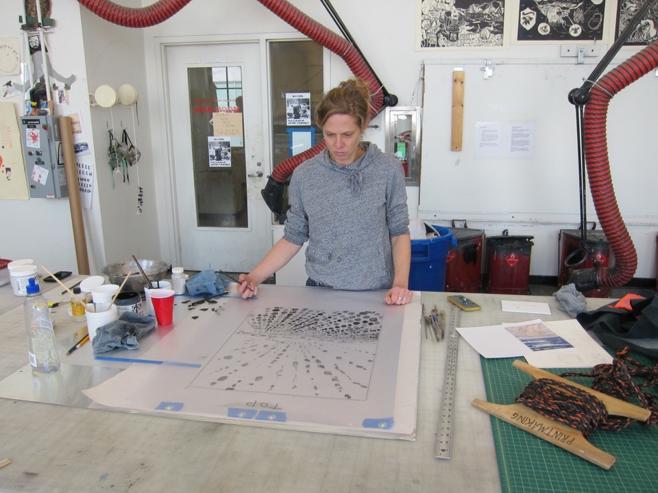 artist in the print shop drawing on plate