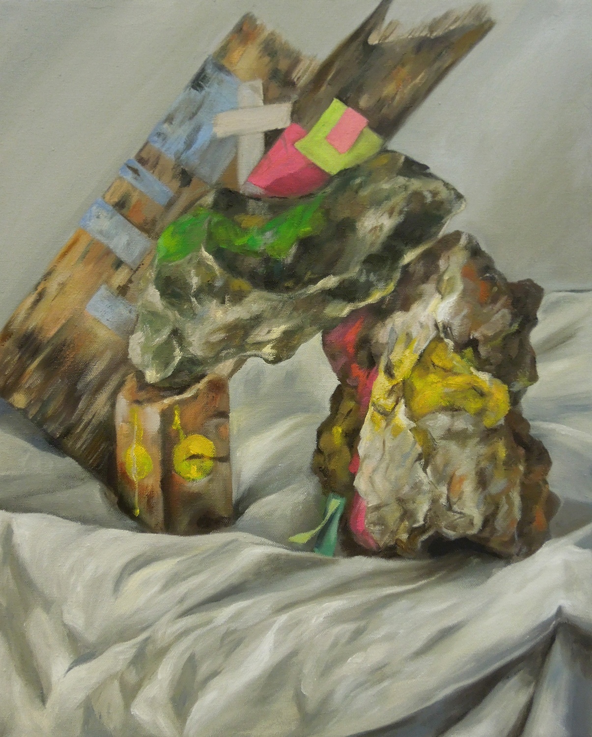 Abstract still life painting of a rock and pieces of wood and brightly colored paper on a clean cloth.