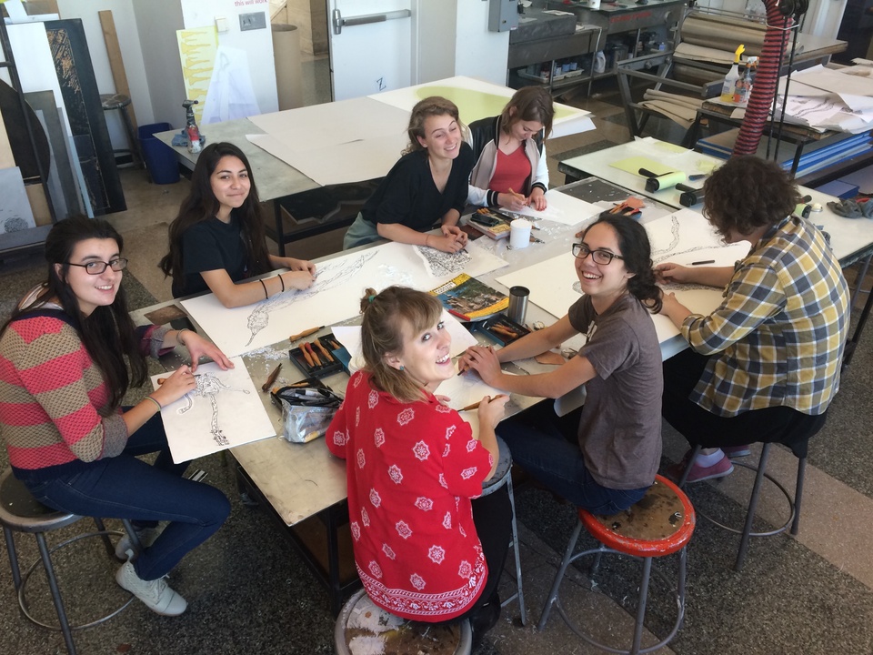 students sitting around a large table working on the artist's project