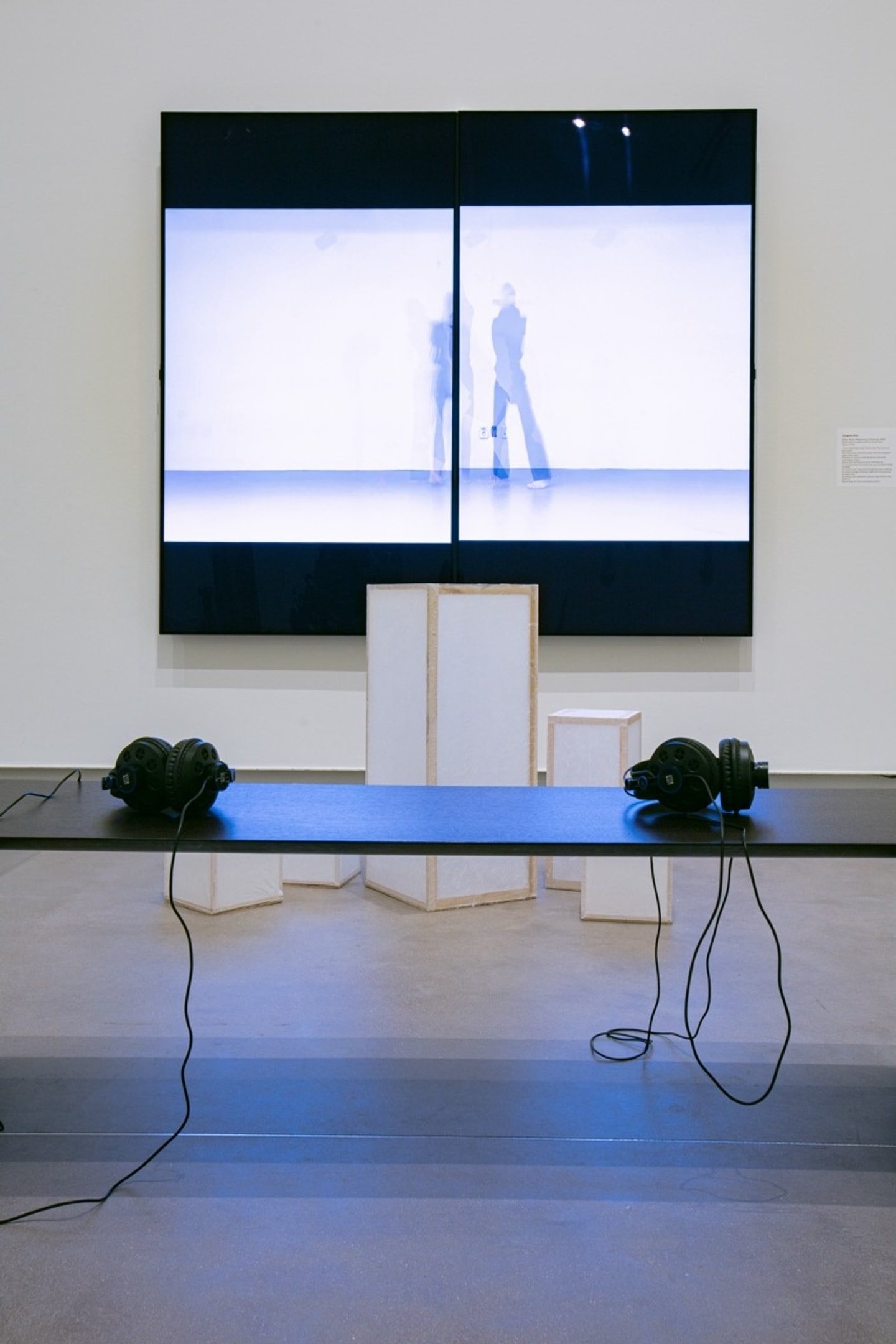 bench and white box sculpture in front of large screen
