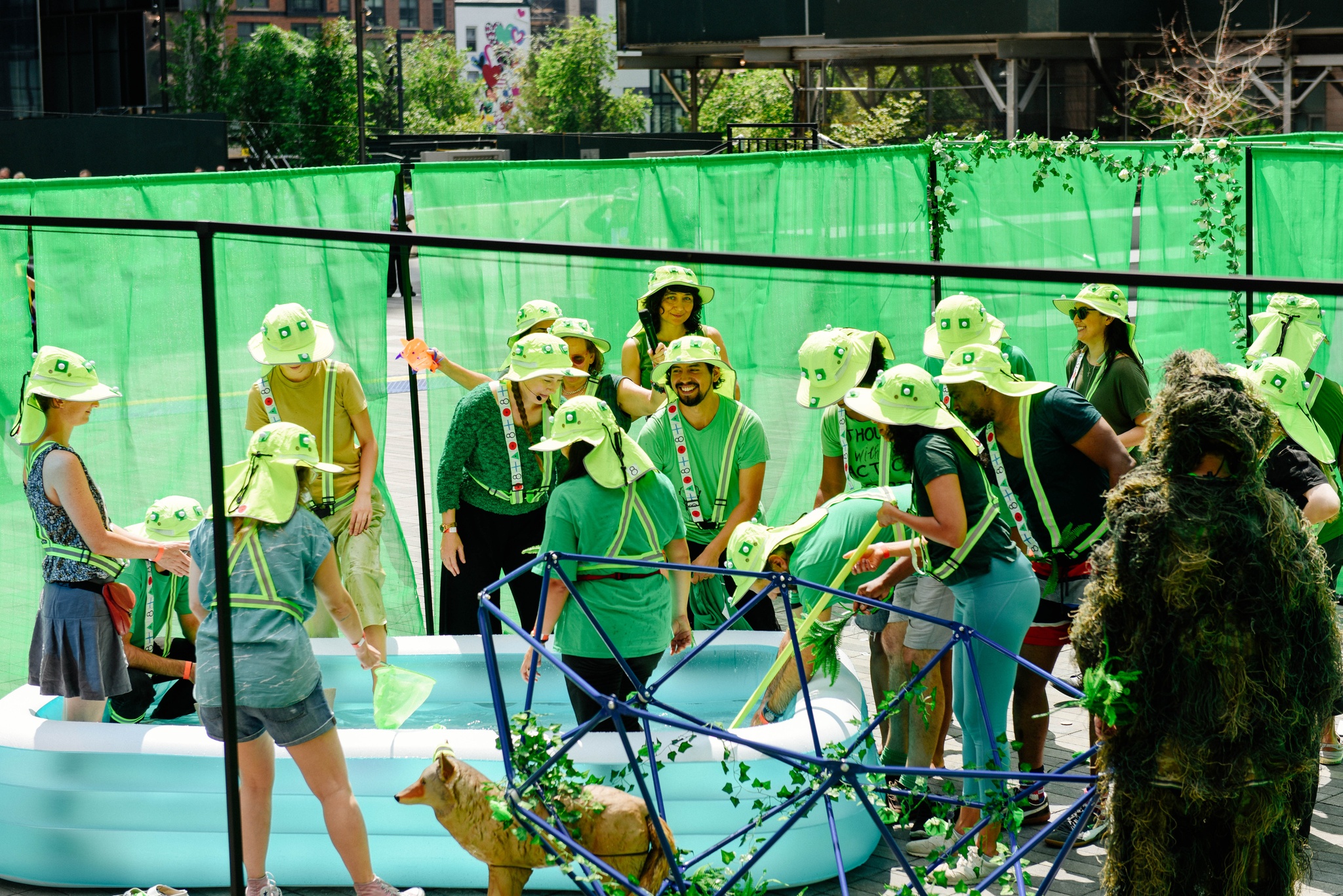 A group of participants in green hats around a kiddie pool.