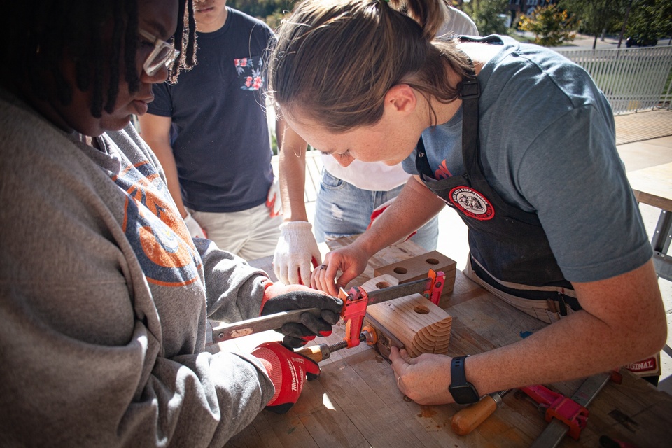 Two students work on clamping a large block of wood