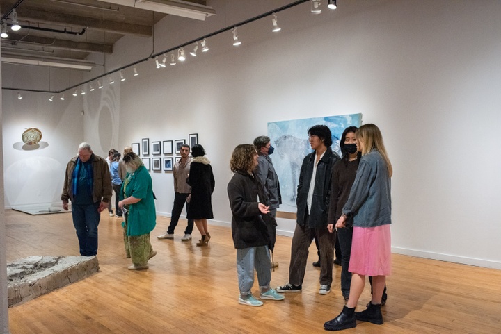 Visitors stand in a gallery space and chat.