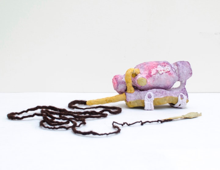 Purple yellow paper mache object shaped like a tiny cement truck