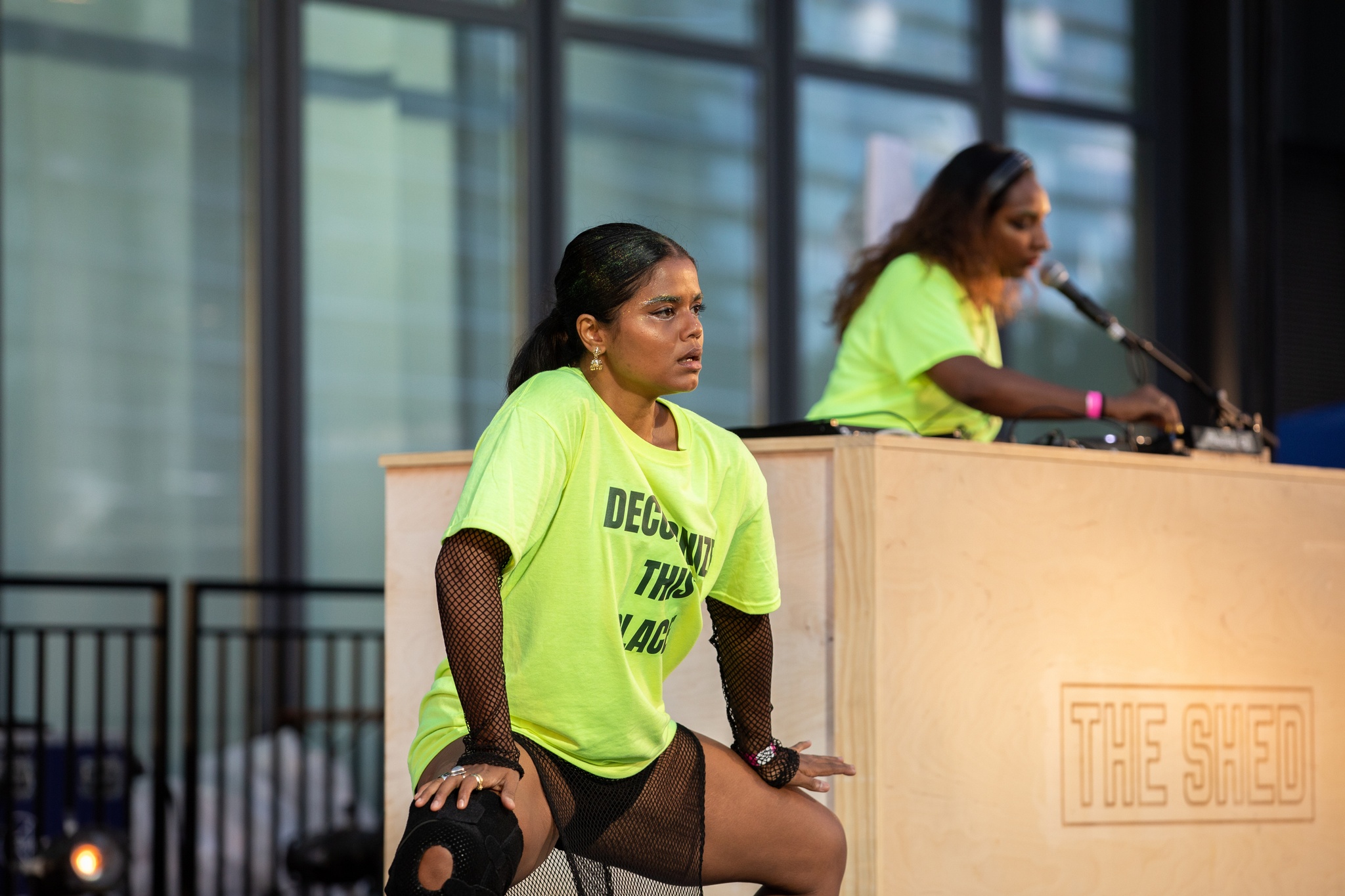 Dancer and DJ performing on outdoor stage.