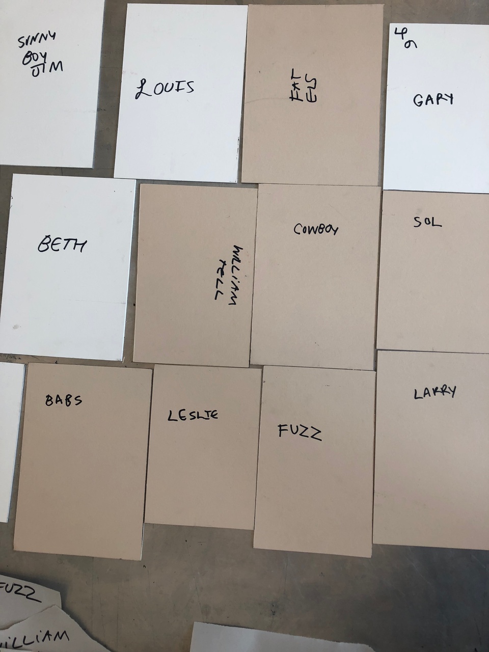 The back sides of 12 printing plates with handwritten names identifying each one.