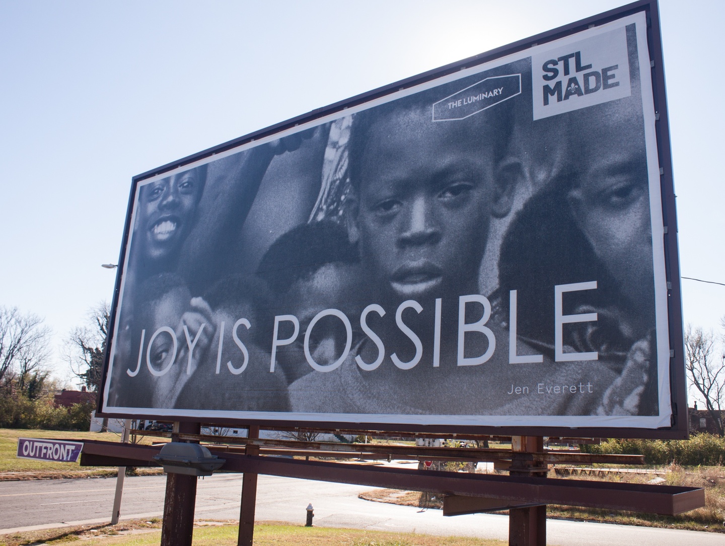 Black and white image of children with text joy is possible on billboard