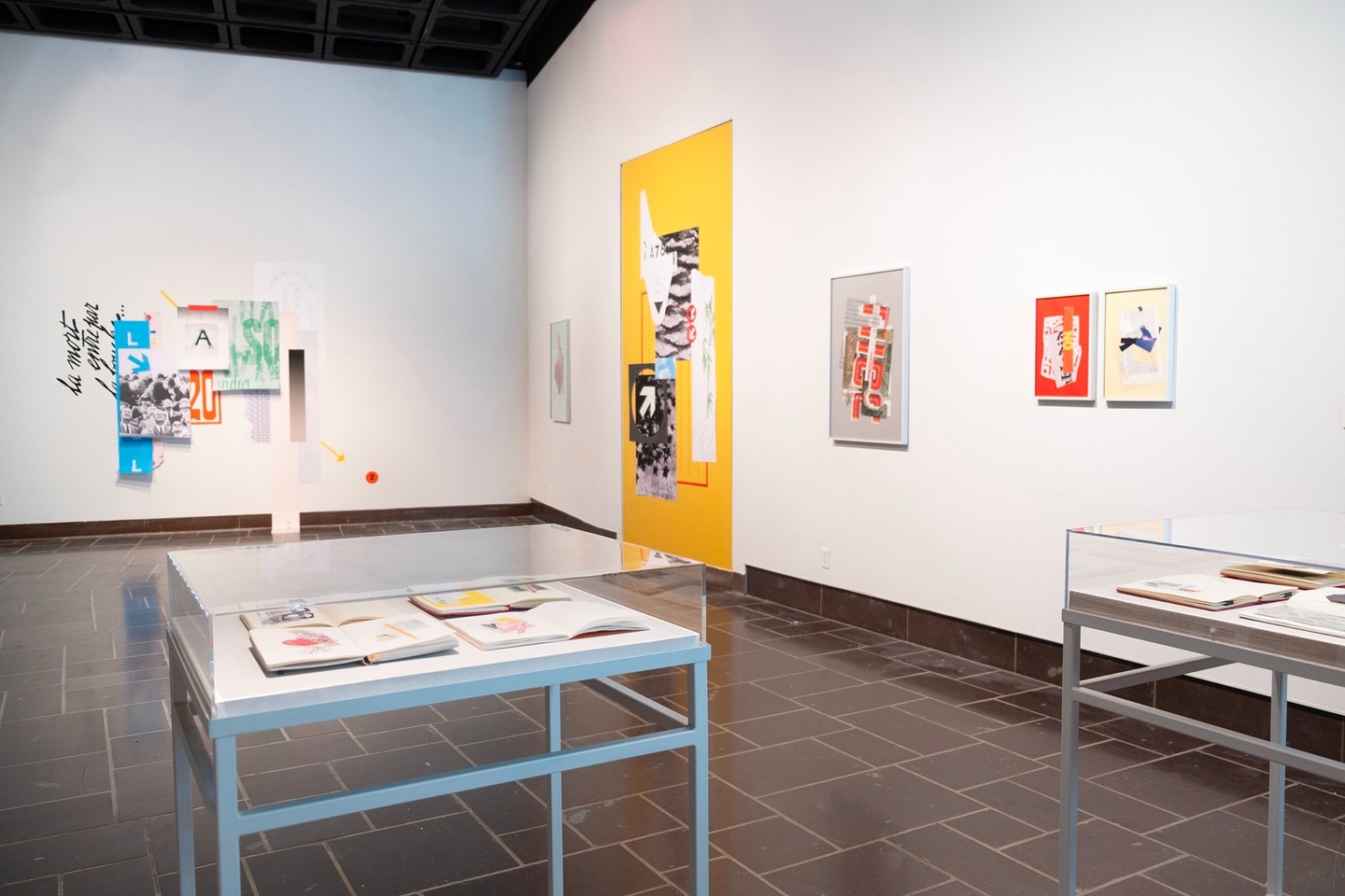 gallery with bright prints displayed on white walls and two table displays