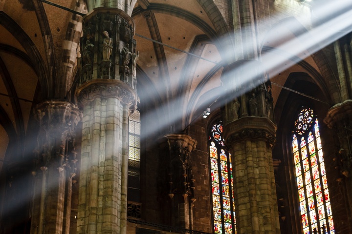 church interior with stained glass windows, sunlight streaming in.