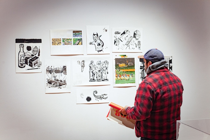 A visitor looks at goache sketches on the wall