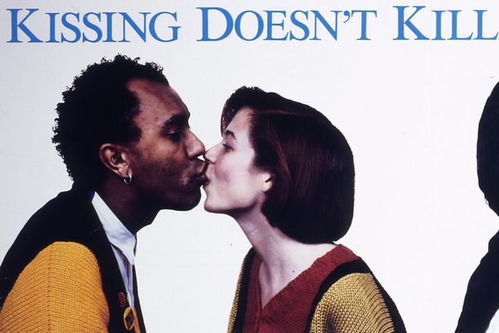 Artwork detail of a couple kissing with the word Kissing Doesn't Kill in blue type above them.