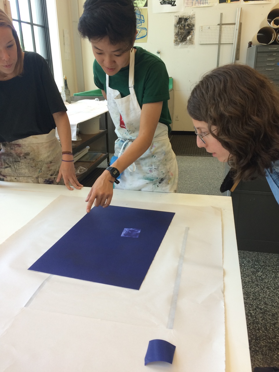 3 people looking at a print on the press