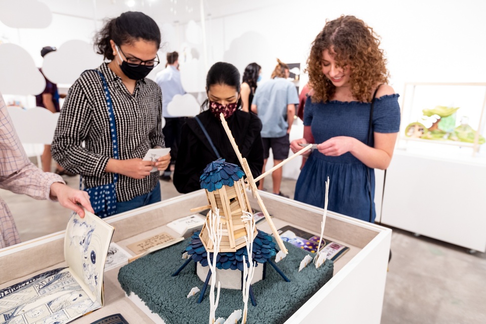 Visitors look at books on a table surrounding a small windmill sculpture