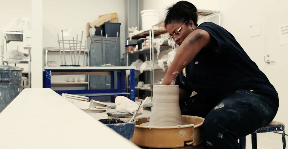 Jamie Harris in at the pottery wheel in the ceramics studio, working to shape clay.