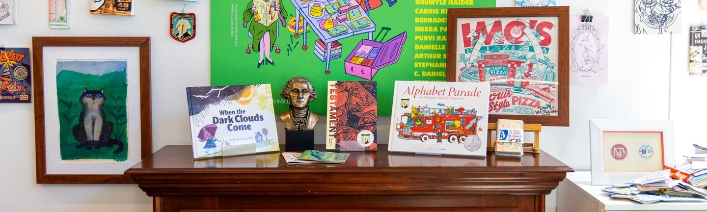 Several illustrated books on display on a fireplace mantel