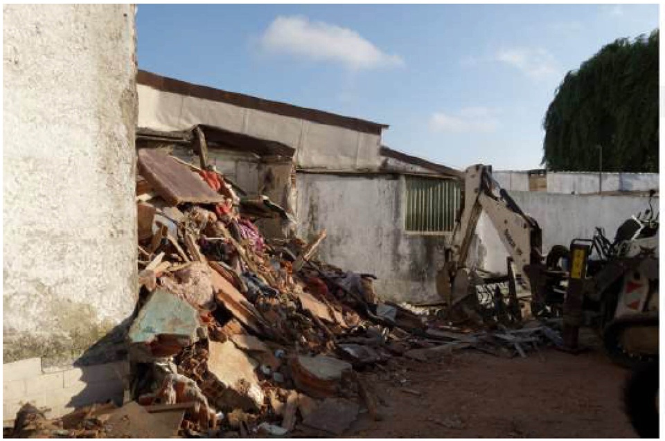 Photo of what appears to be the side of an old, white building, either partially demolishing or falling apart. 