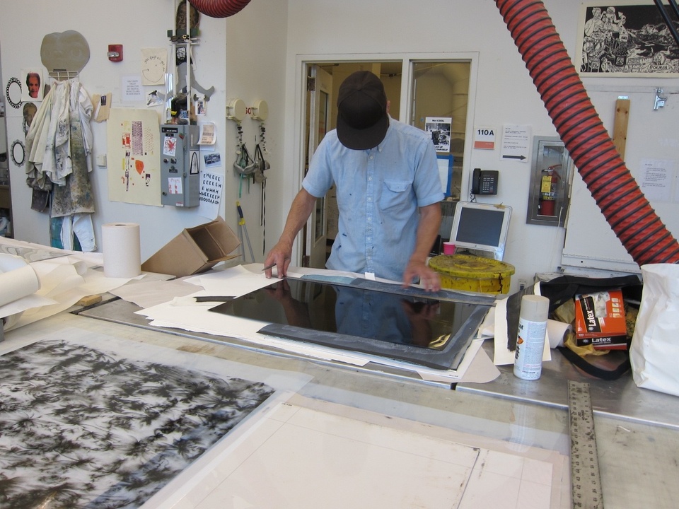 Shaun holds up a ruler against a large print on the table 