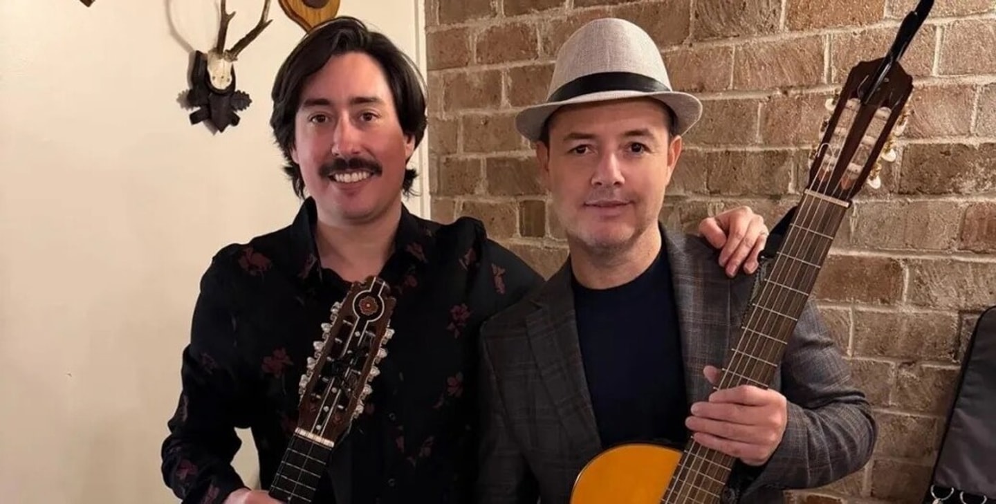 Photo of two musicians side by side holding acoustic guitars