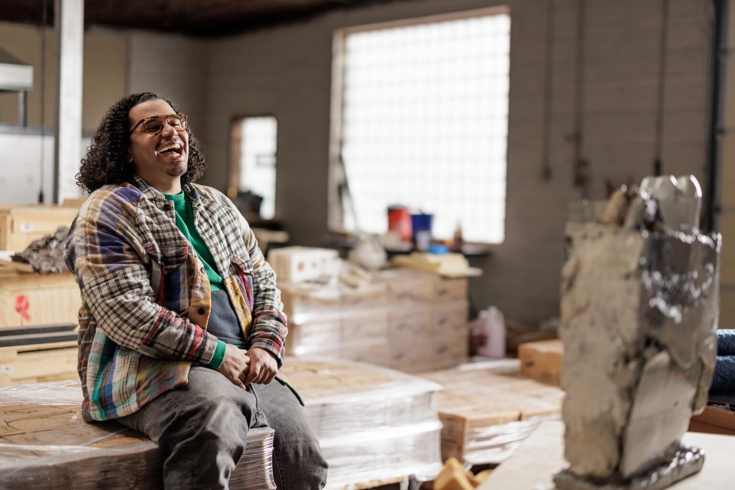 Man seated in an artist studio, laughing