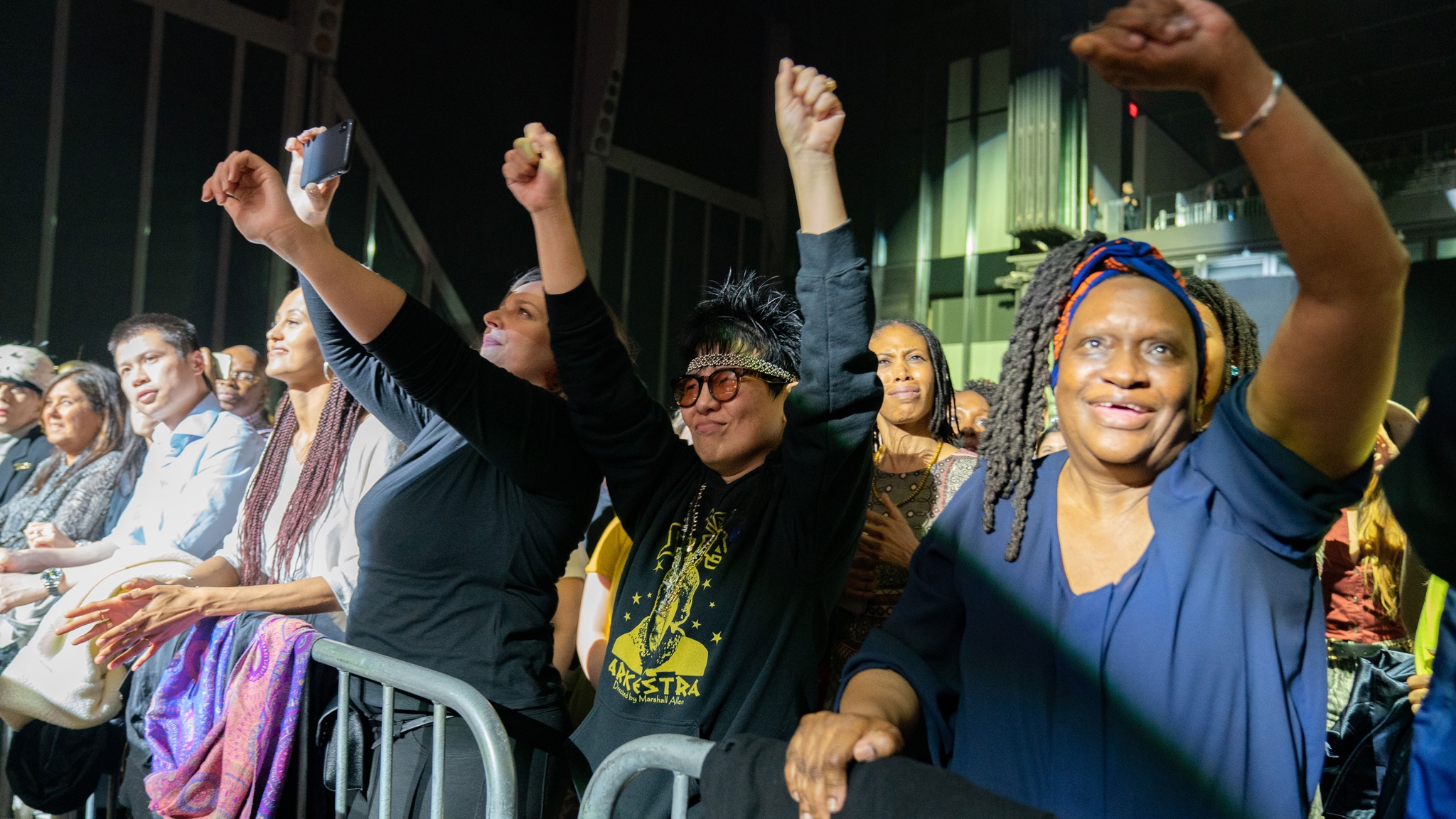 Joyful audience members at event with their arms in the air.