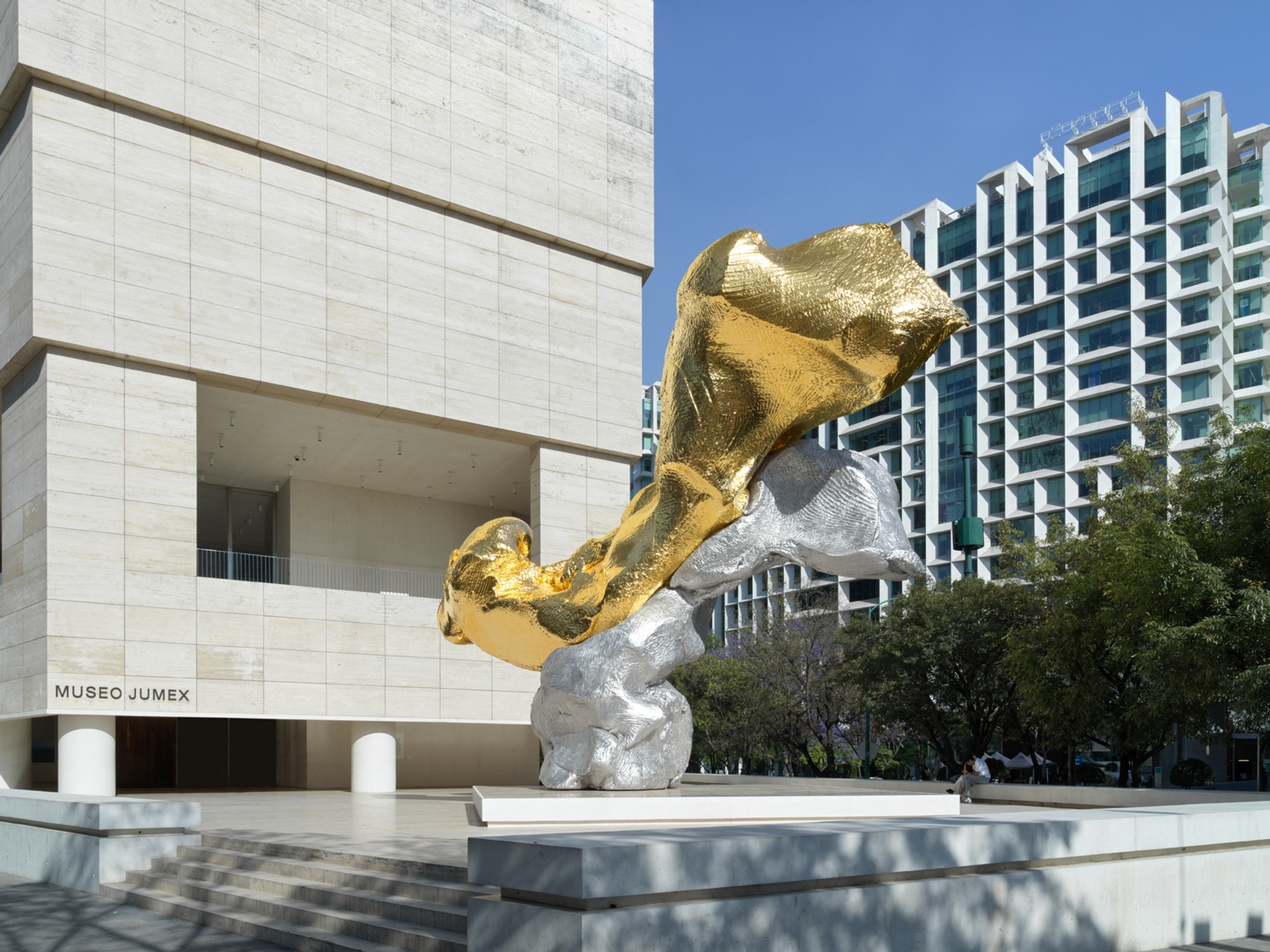  Exterior del museo Jumex, donde enfrente de la entrada hay una gran escultura moderna, de forma irregular color dorada