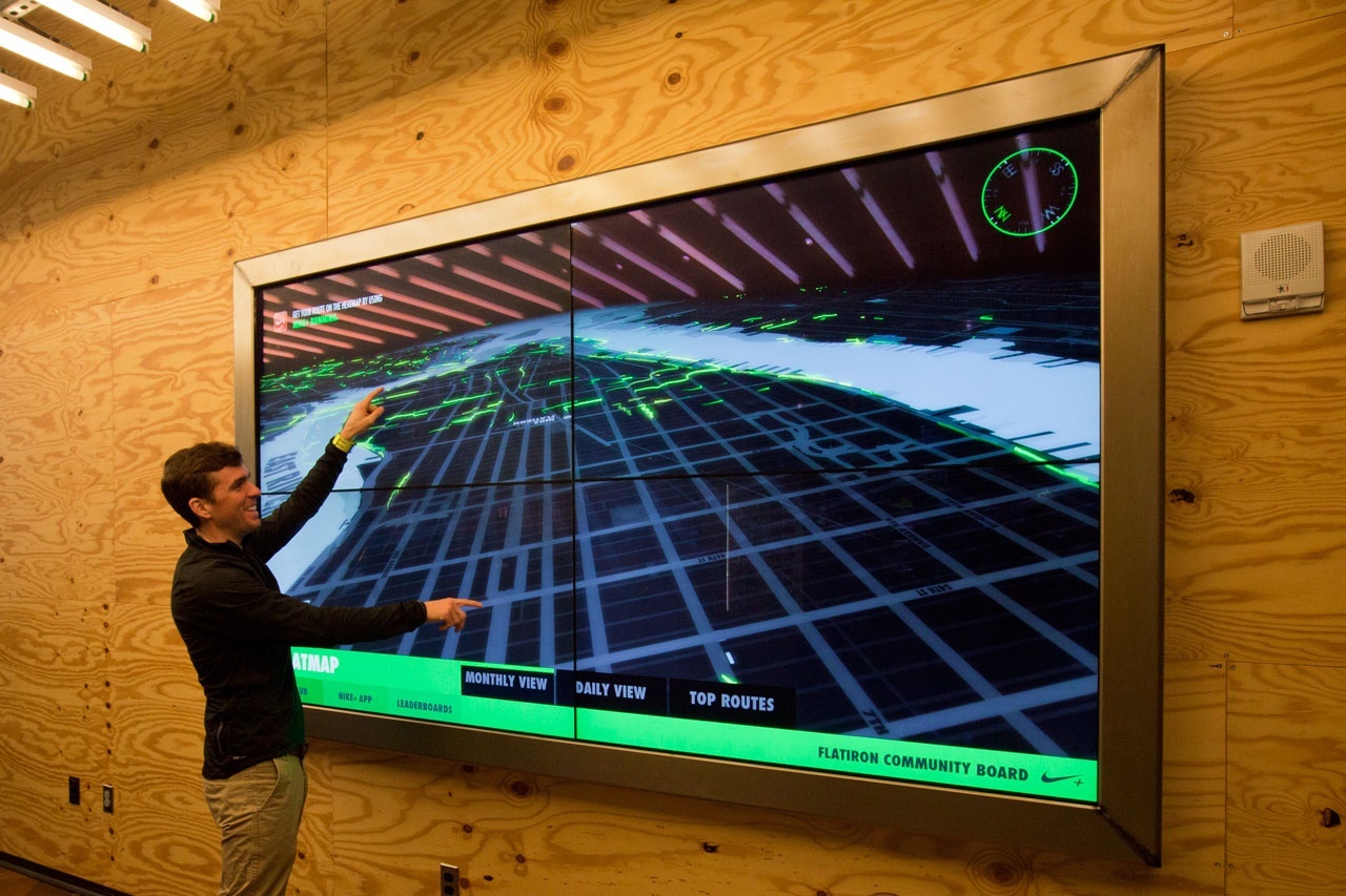 Person pointing at a TV screen which displays the heatmap, the running data visualization of runners in the area