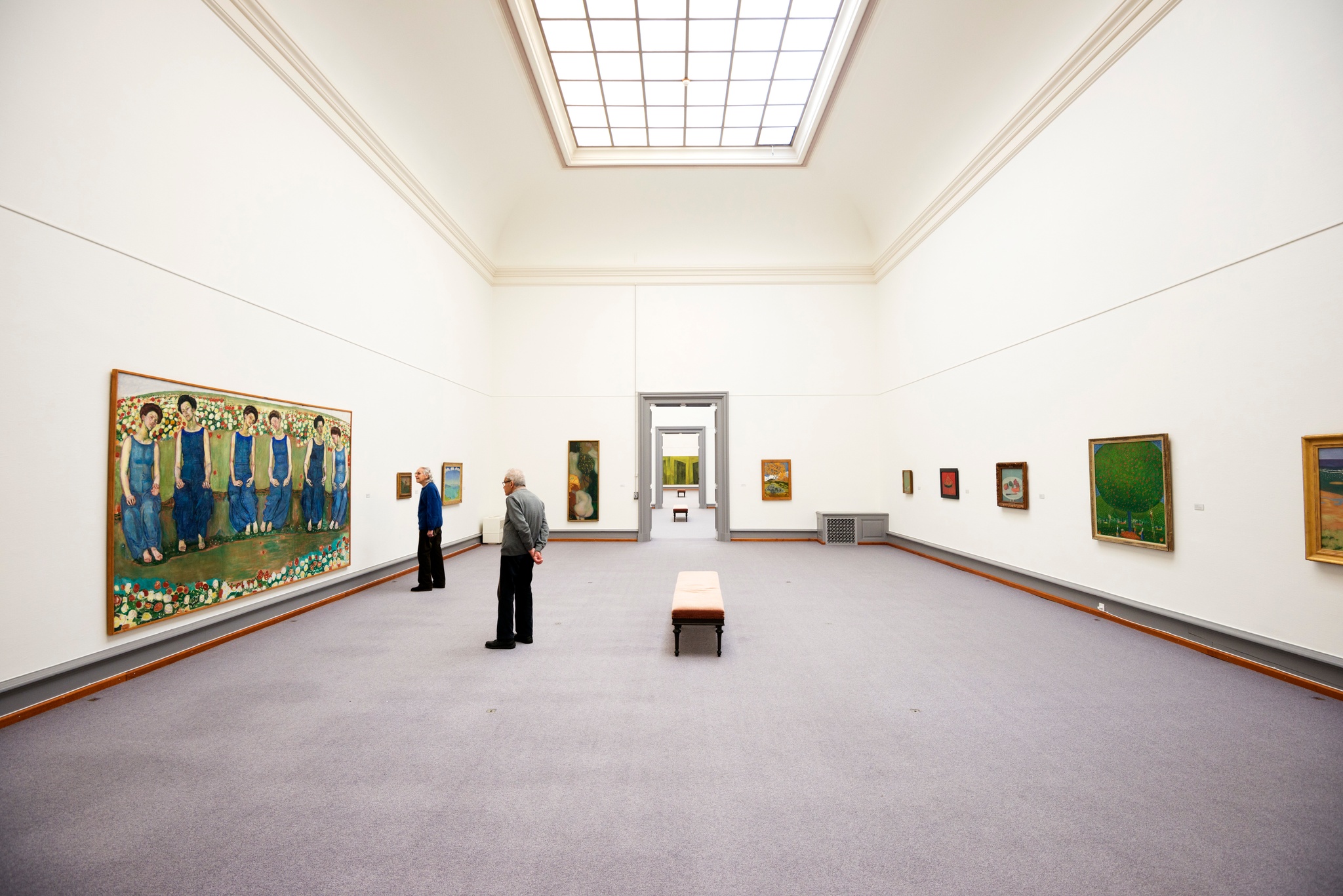 Two men look at a painting in a large white-wall museum gallery