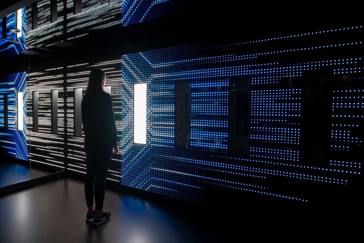 A person standing in front of wall displaying light patterns 