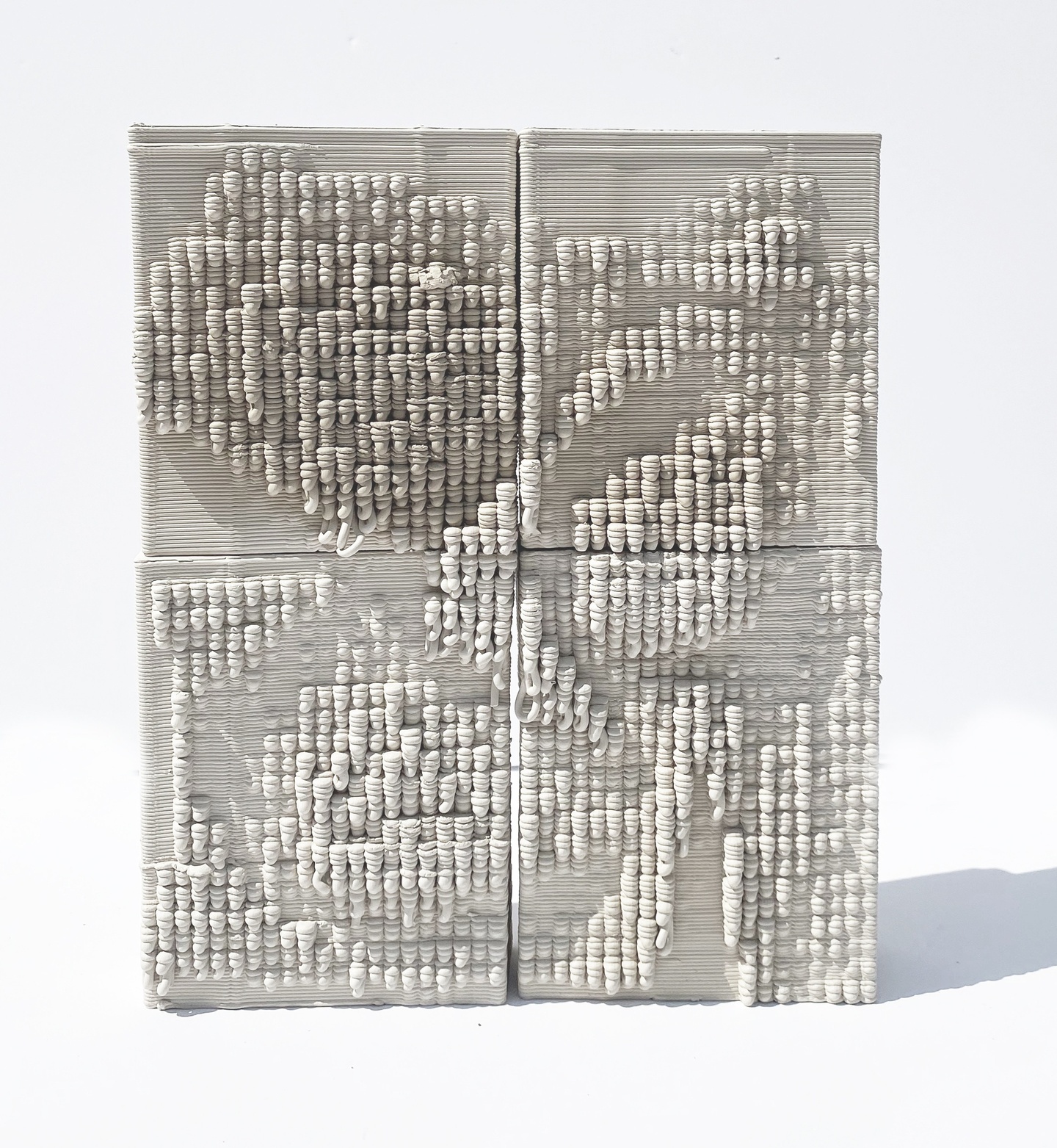3D-printed white ceramic piece that square in overall shape, with lots of grooved, rounded surfaces protruding.
