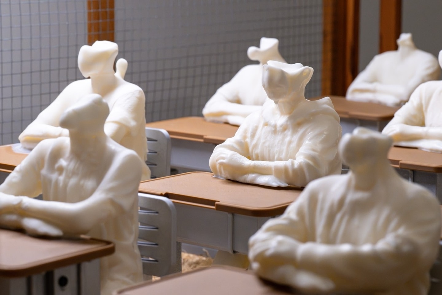wax headless figures sitting in a classroom