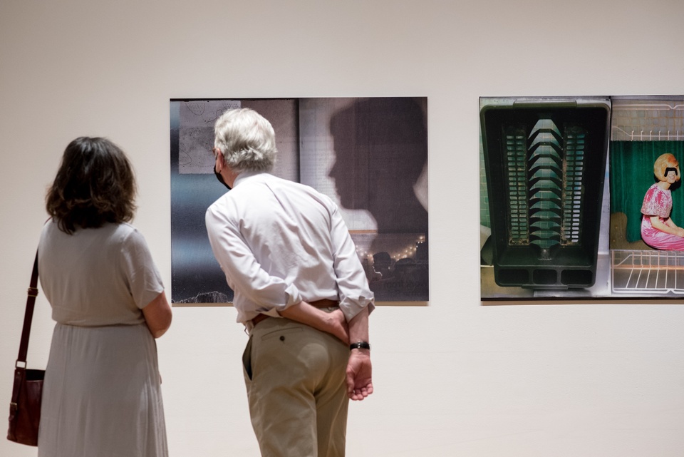 Two gallery visitors view collage prints by Michael Byron