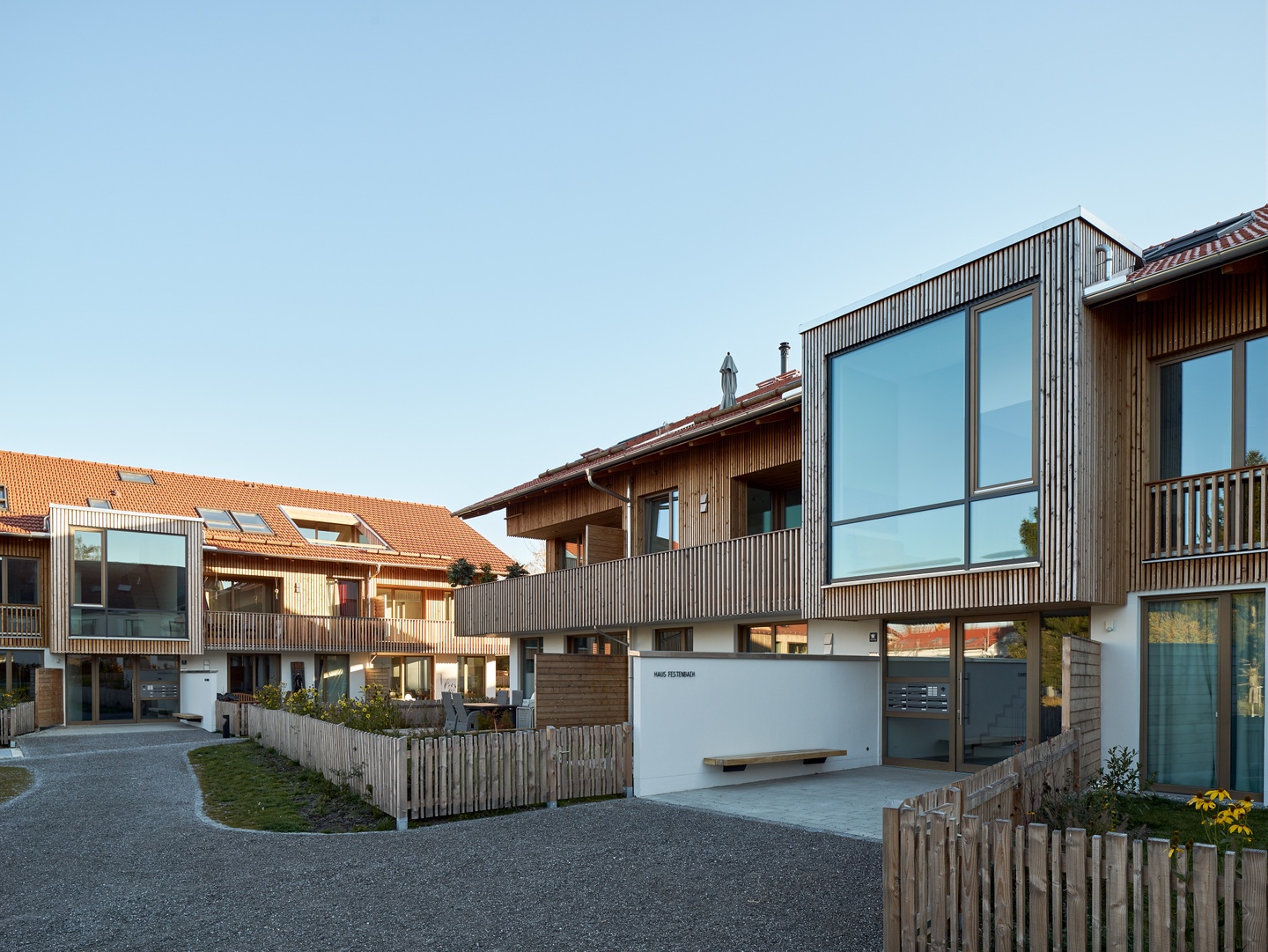 Modular single-family housing units with two levels, rustic wood siding, large windows, and sky lights.