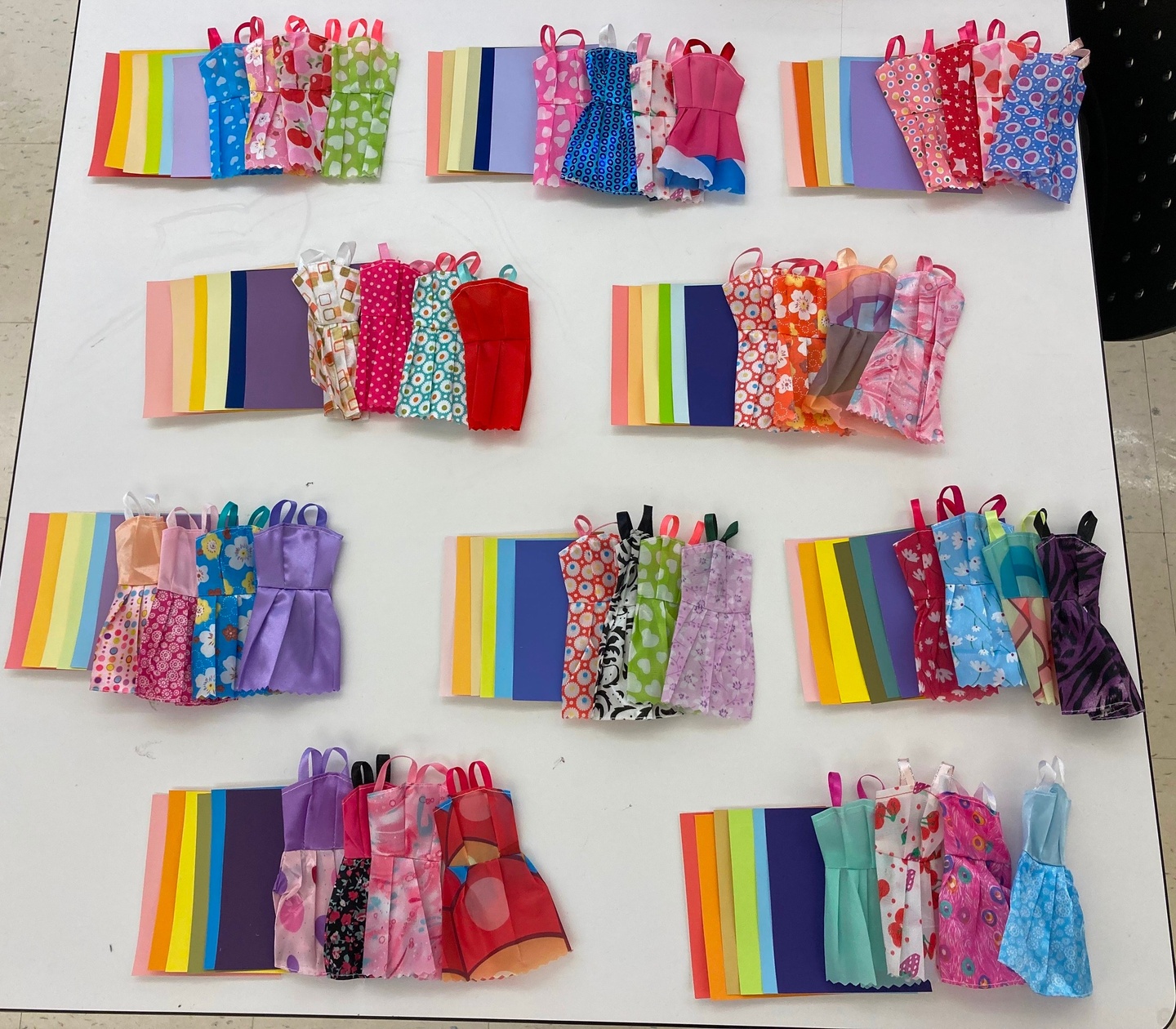 Fabric swatches and small dresses laid out on a table.