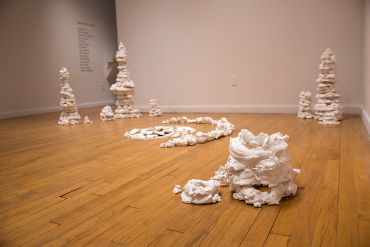 Several 2-3' totems of lumpy white plaster are assembled purposefully around a central display of plaster shards arranged in a crescent and circle shape.
