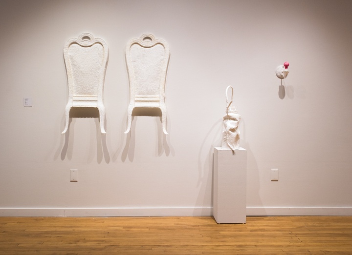 Plaster casts of two fancy dining chair backs mounted on the wall; cast of a crumpled spray canister on a plinth; and a cast of a naked lightbulb and fixture mounted to the wall.