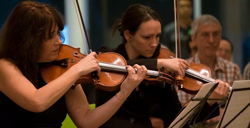 A photograph of two people playing violin
