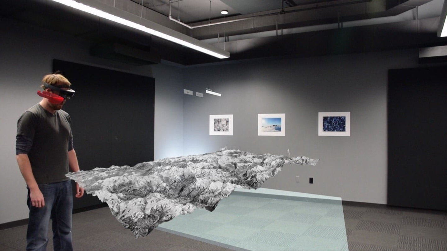 Person wearing special viewing goggles looking at a textured model suspended in the air.