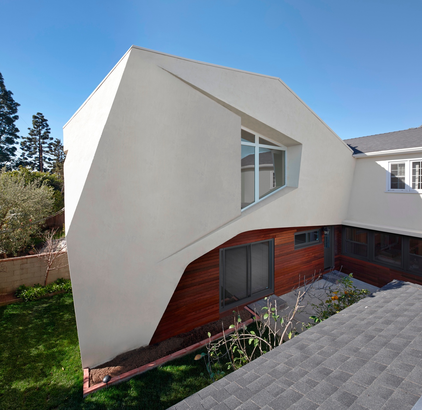 Exterior of a house with a white stucco wall projecting at unusual angles.