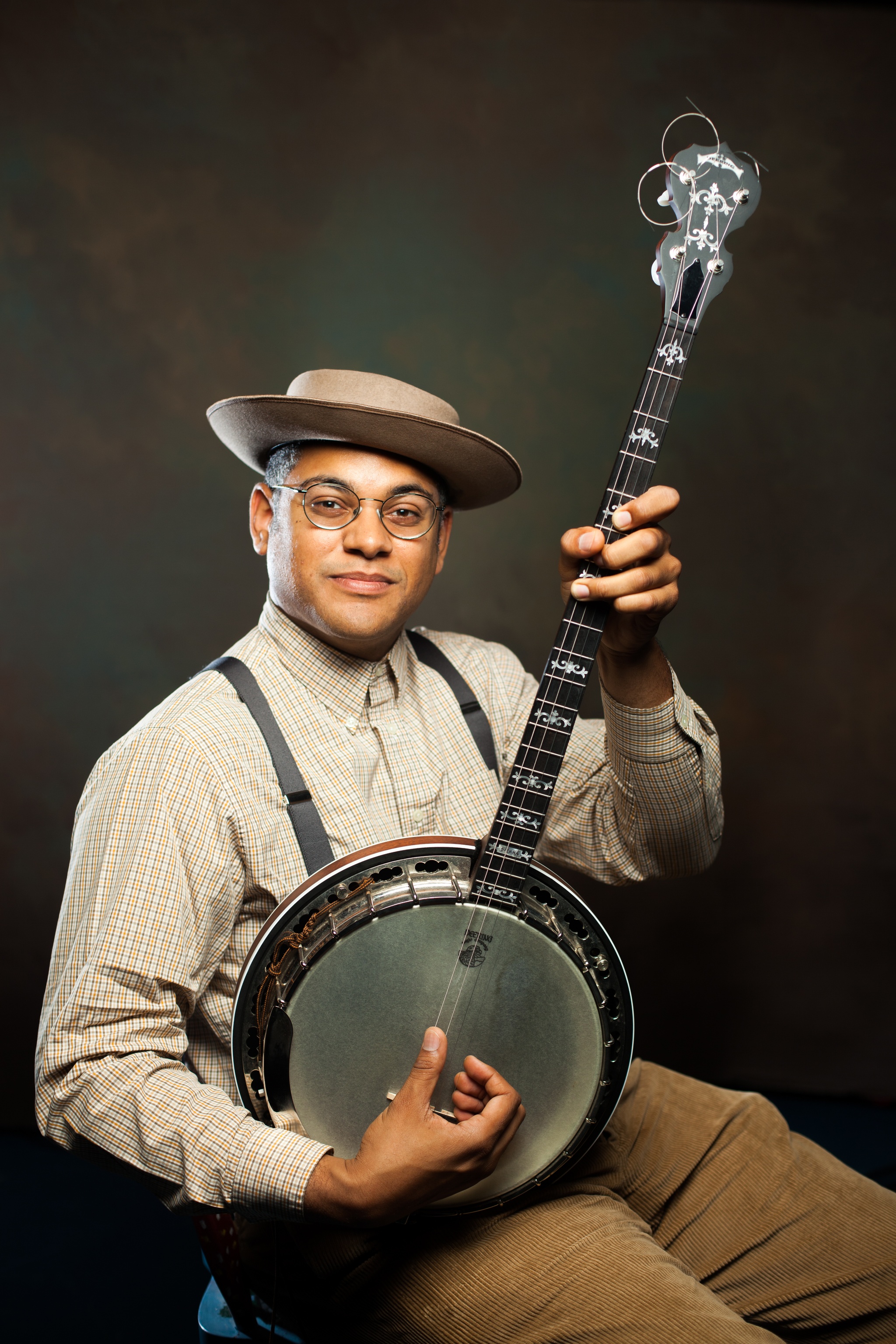 A portrait of Soundtrack of America artist Dom Flemons posing with a string instrument