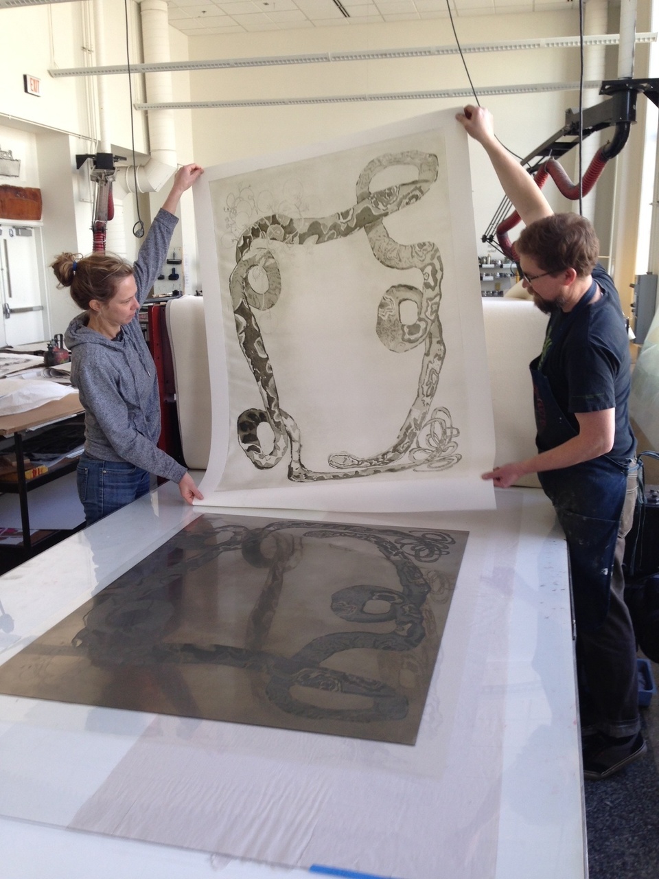 artist and printer at the press lifting proof of snake image from the plate