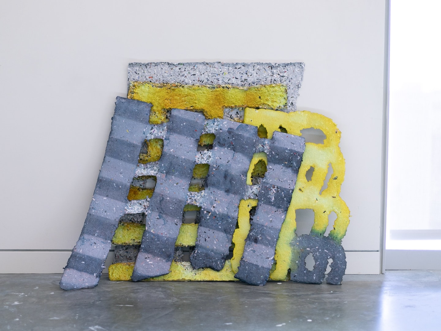 large sheets of purple and yellow handmade paper leaning against a wall