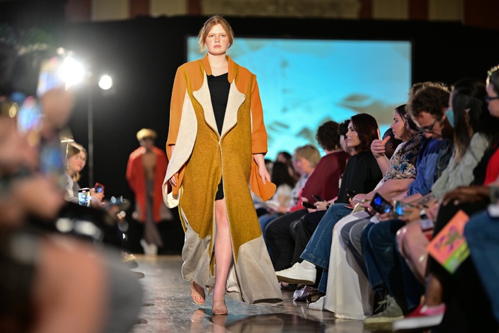A model walking down the runway in large yellow jacket