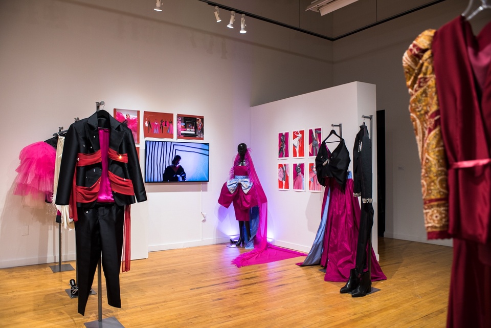 Collection of lavish garments in magenta and black. One is lit with colored lights.
