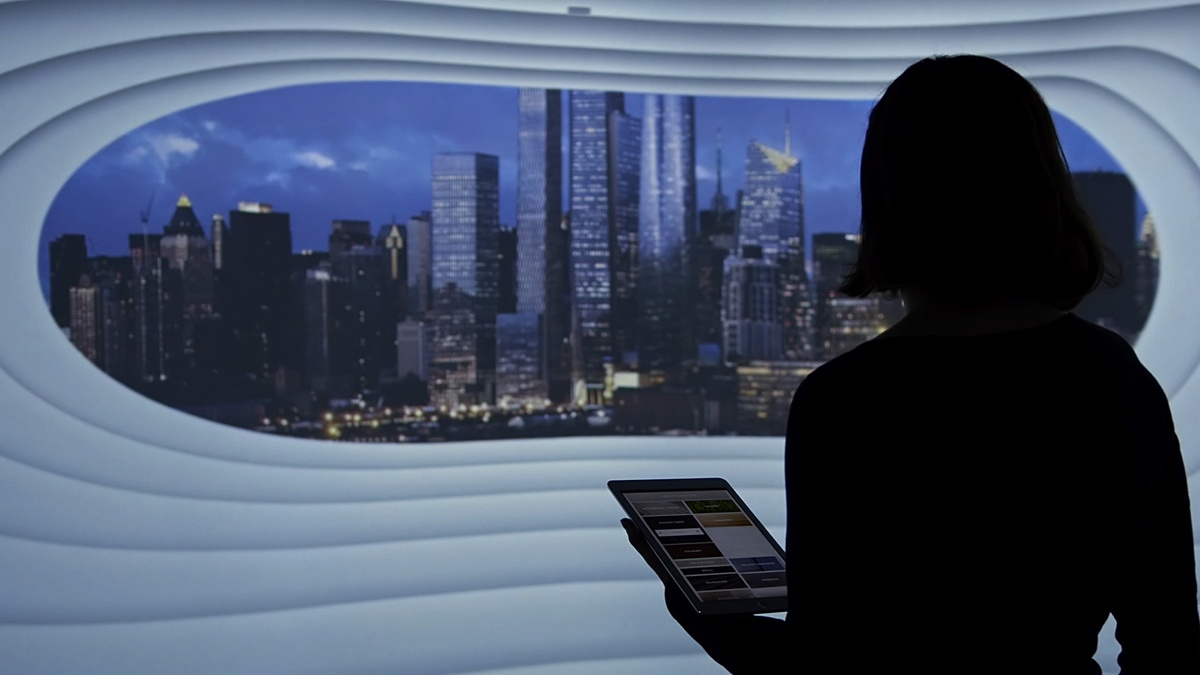 Woman holding a mobile device looking at a nighttime skyline on the curved screen