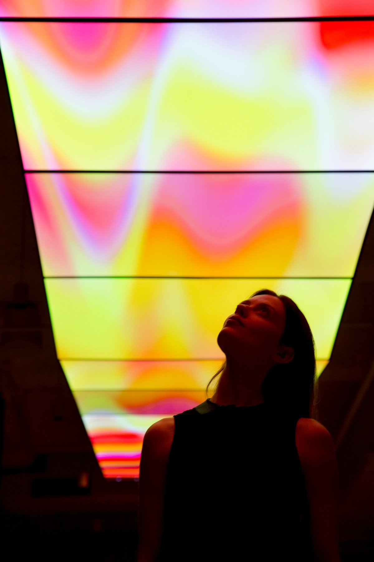 Close-up of a woman looking up at the Skywalk, displaying waves of white, pink and yellow color