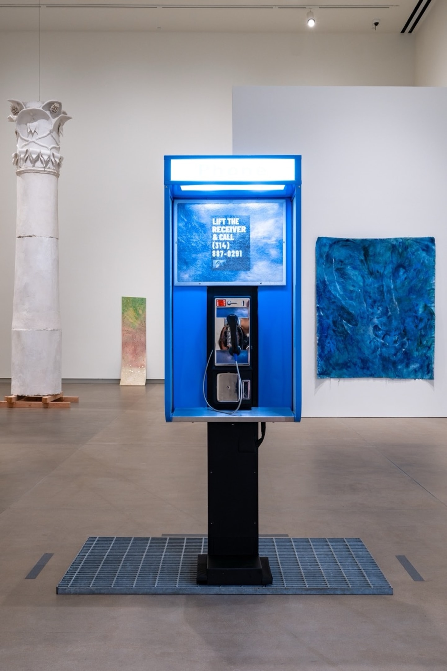 a blue pay phone on display in a gallery