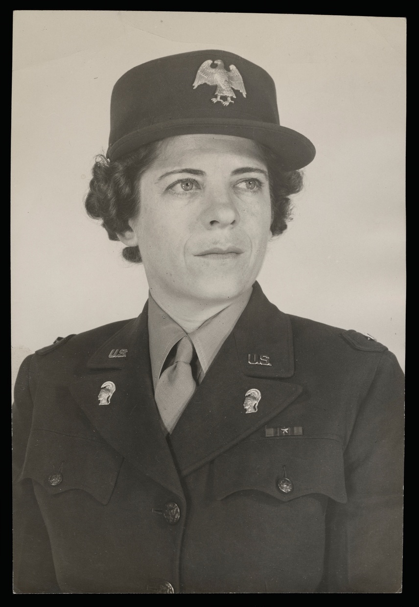A black and white photograph shows a young light-skinned woman in an army uniform. She has short hair, light eyes, and is not looking at the camera.