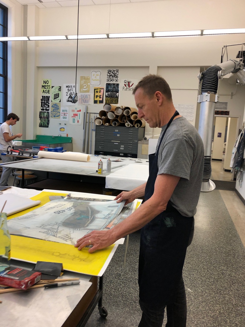 David laying out large prints on a table in the print shop