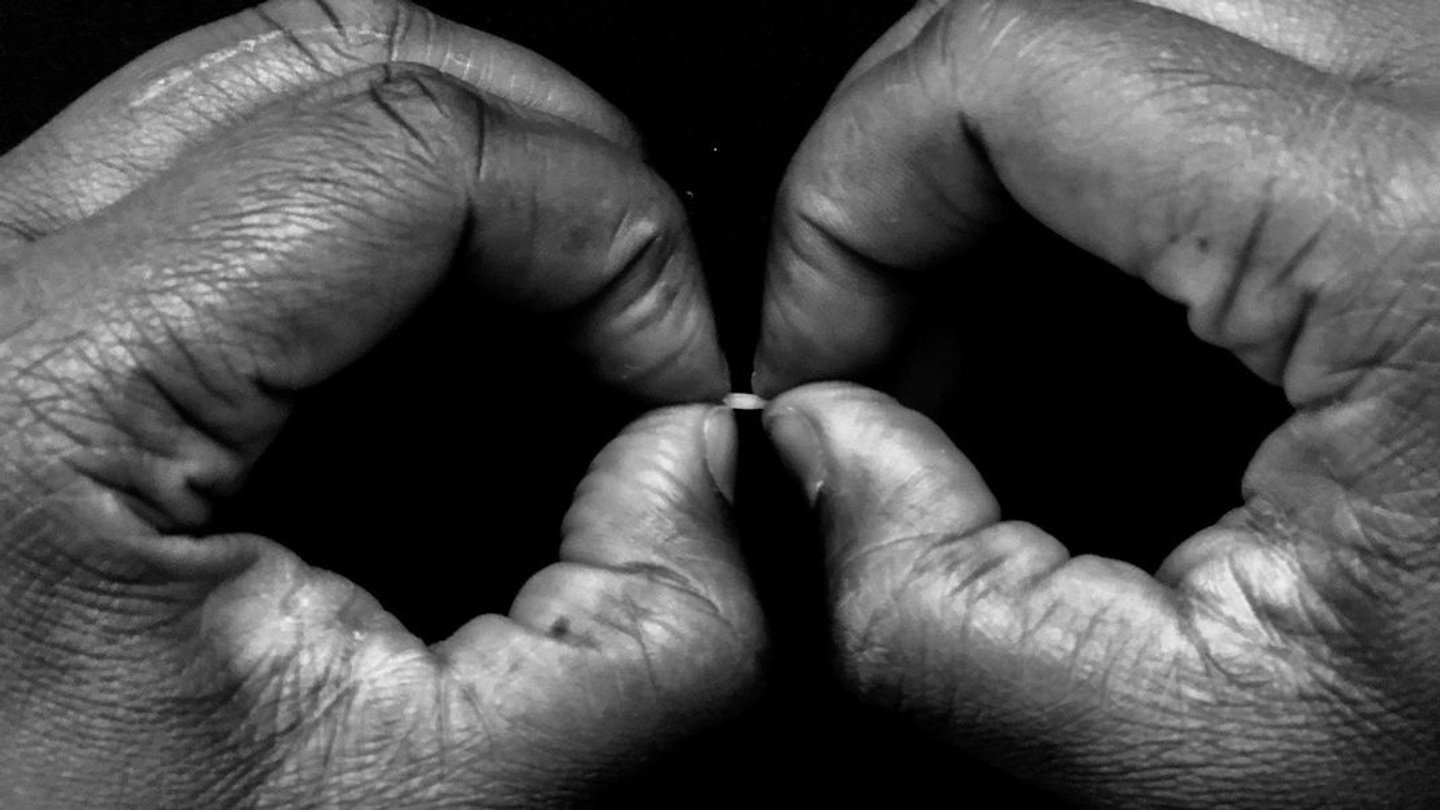 Close-up of fingers grasping a grain of rice